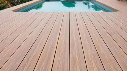 A rectangular pool with clear water is surrounded by a wooden deck.