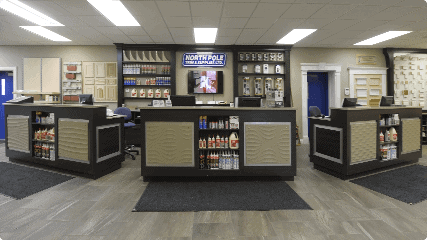 A hardware store counter area with display shelves featuring various products, three service desks, and signage above promoting paint and other hardware materials.