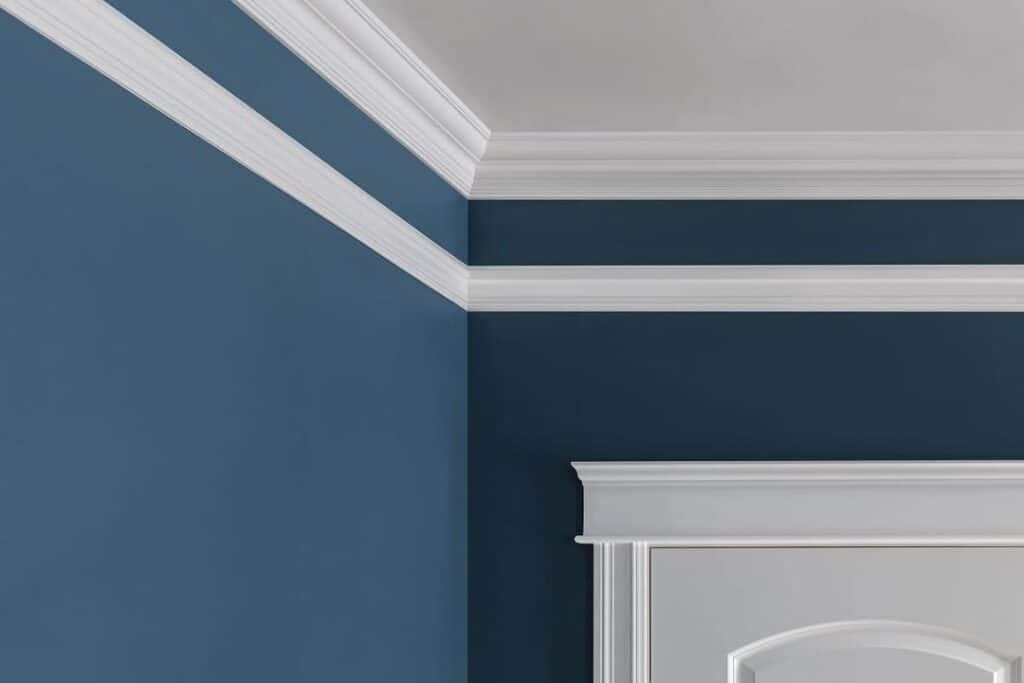 White crown molding on a blue wall with a white-framed door.
