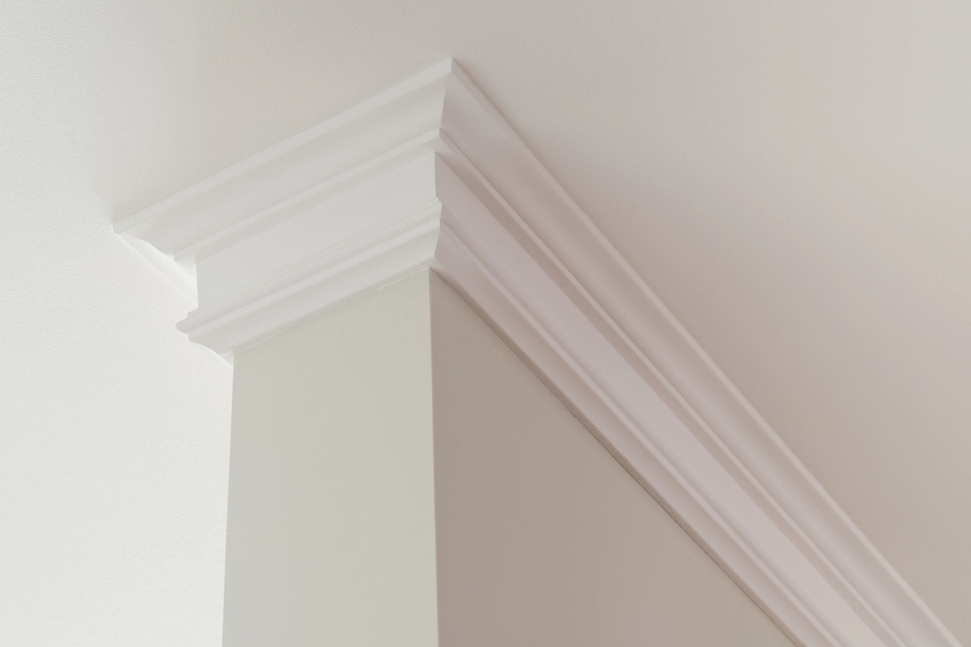 White crown molding at the intersection of a beige wall and ceiling.