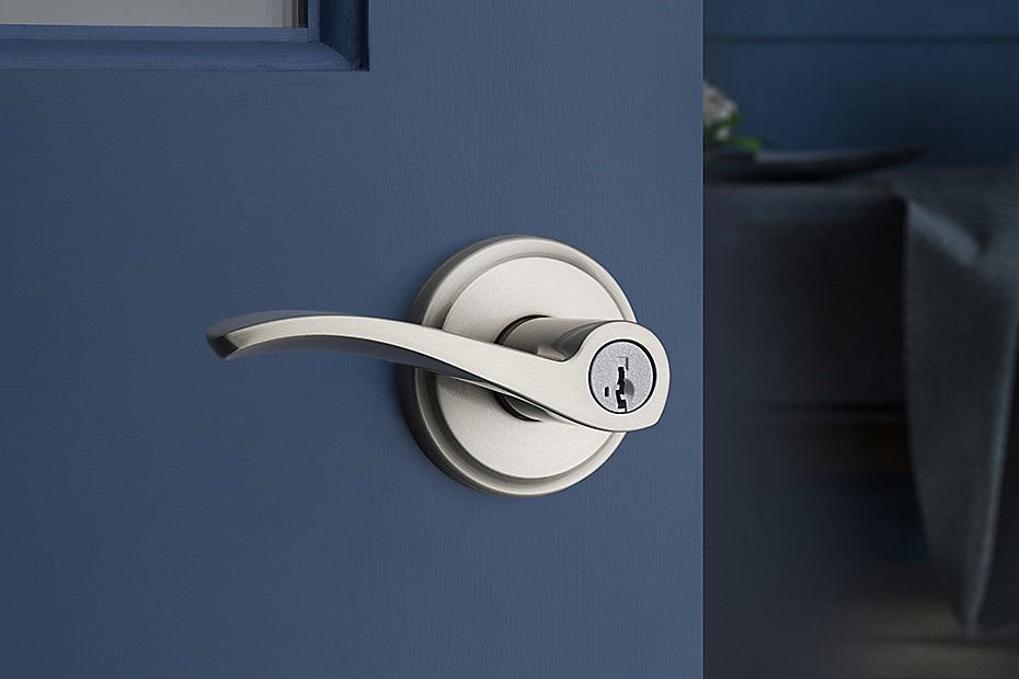 A sleek piece of door hardware, the silver handle with a keyhole gleams against the vibrant blue door.